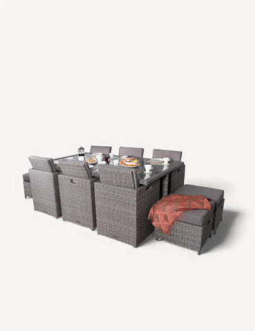 Grey rattan outdoor dining set with chairs, stools, glass table and place settings
