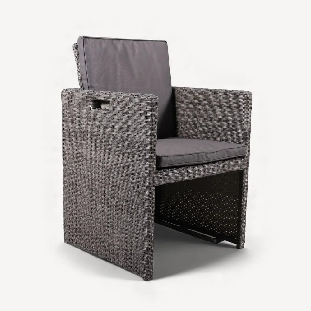 Grey rattan dining chair with armrests and dark seat cushions on white background