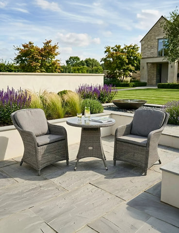 Grey rattan garden bistro set with round table and two cushioned chairs on patio