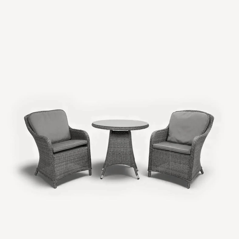 Grey rattan bistro set with two cushioned chairs and round dining table on white background
