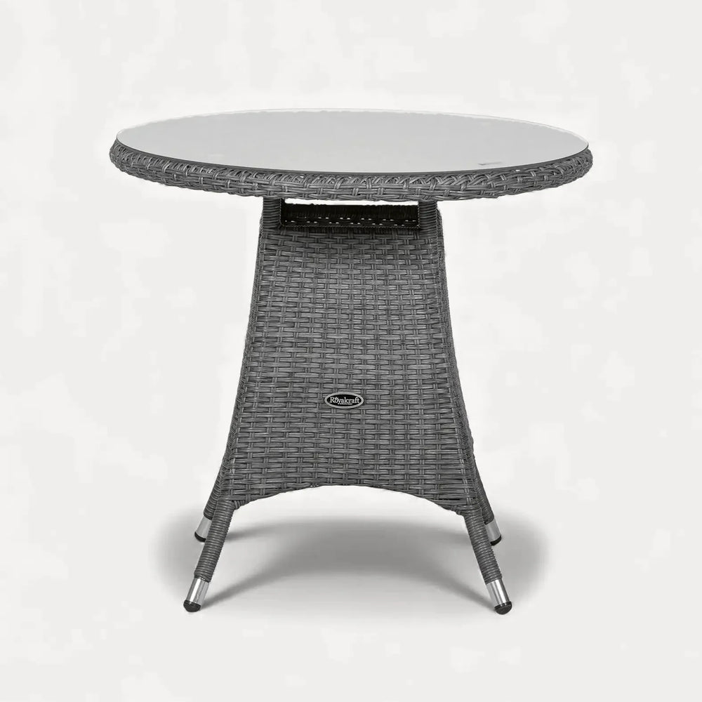 Round rattan garden table with glass top and woven wicker base, angled front view