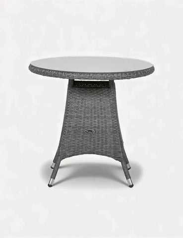 Round rattan garden table with glass top and woven wicker base, angled front view
