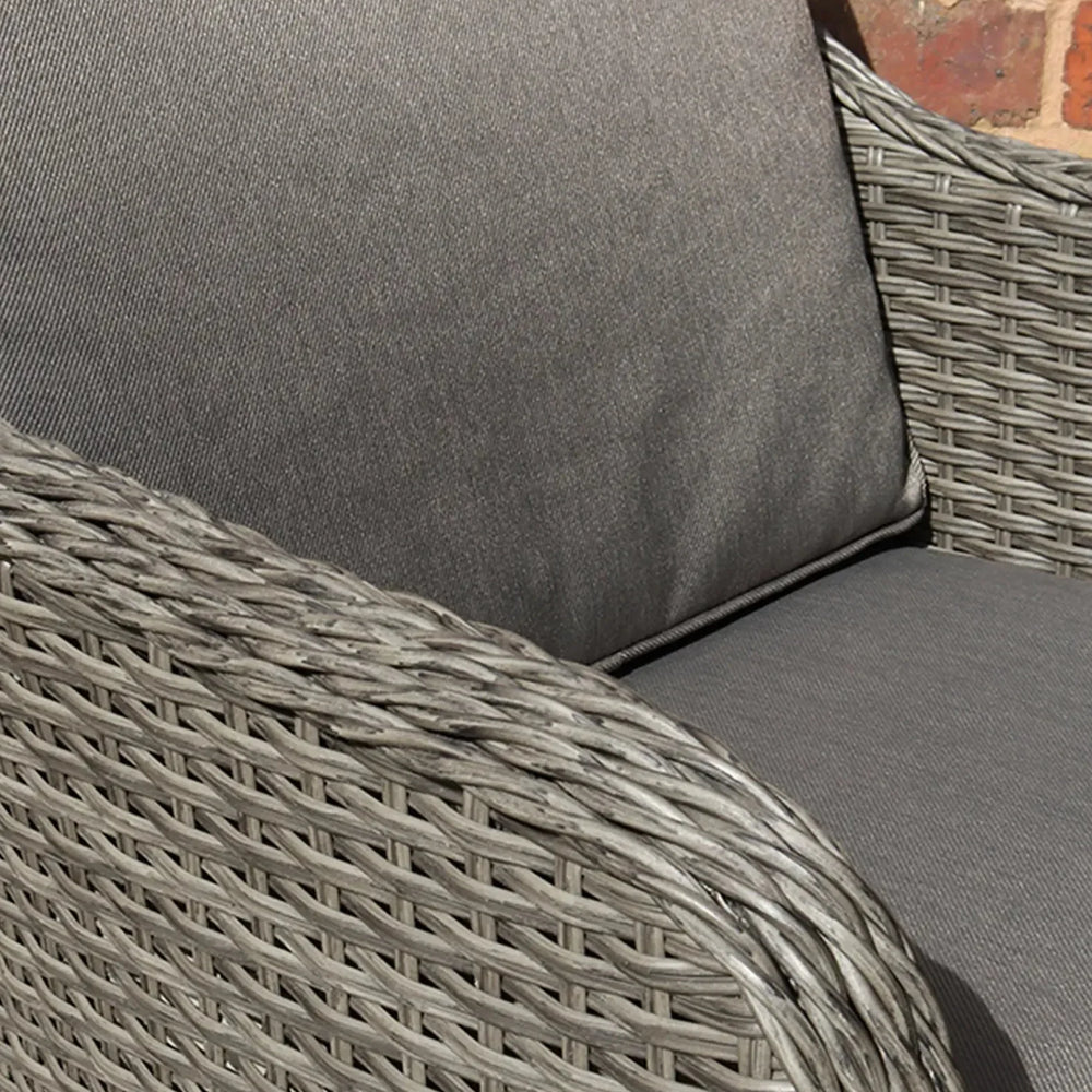 Close-up of grey rattan garden chair with thick grey cushions and woven arm detail