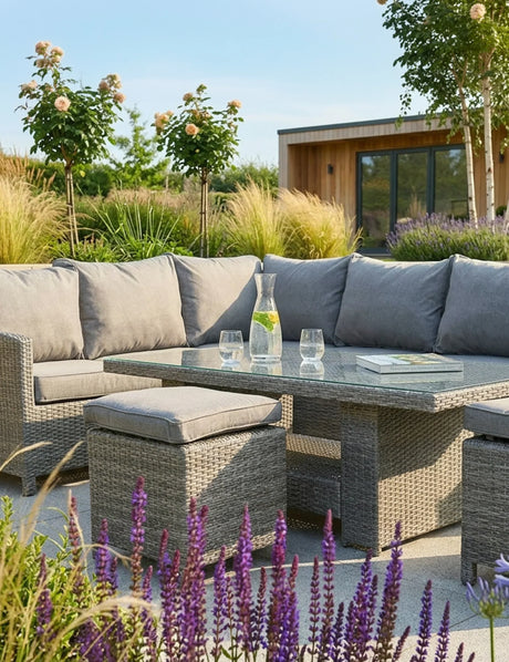 Grey rattan outdoor corner sofa set with cushions and glass top dining table in garden