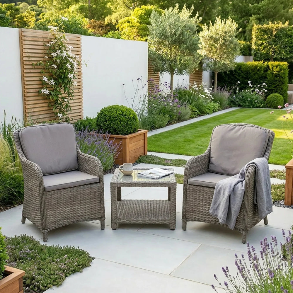 Rattan garden furniture set with two armchairs and table on modern patio surrounded by plants