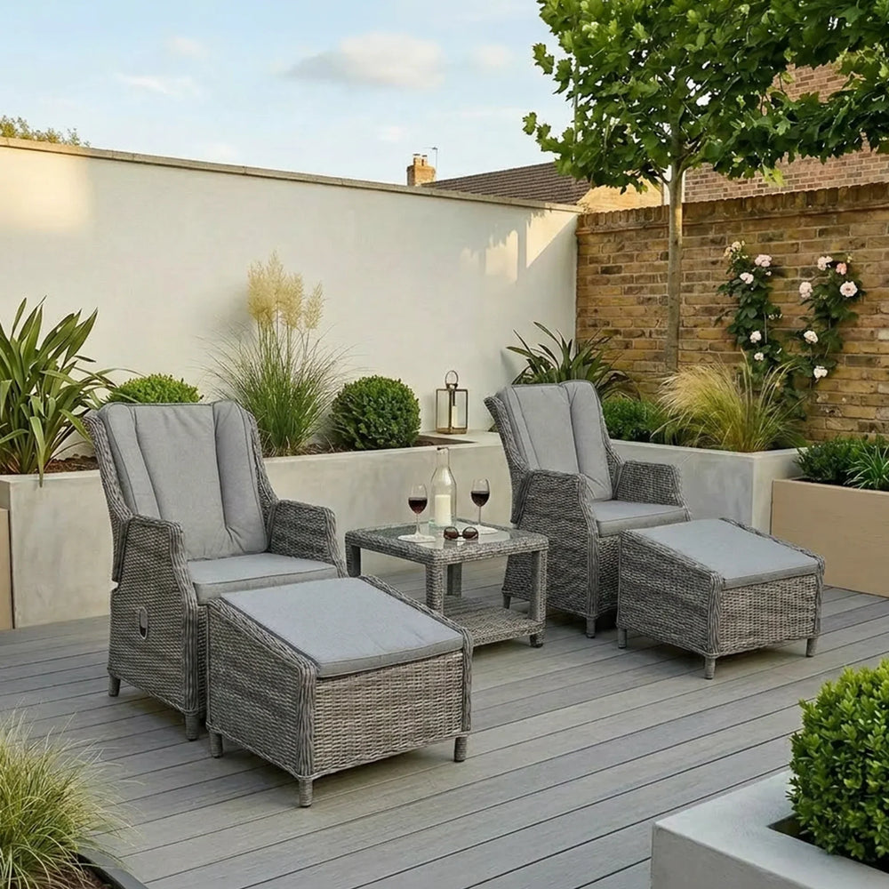 Grey rattan reclining garden chairs with cushions and matching footstools on modern patio