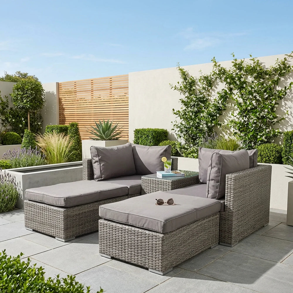 Grey rattan outdoor sofa set with cushions and glass-top table on a modern patio