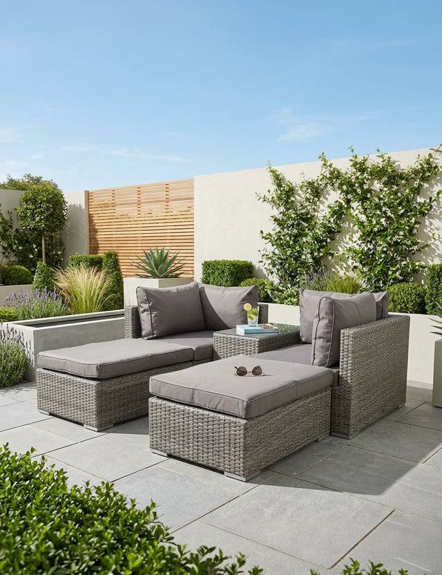 Grey rattan outdoor sofa set with cushions and glass-top table on a modern patio