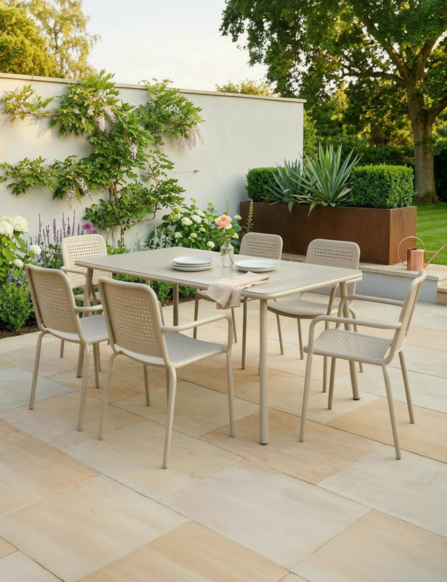 Champagne outdoor dining set with six chairs on tiled patio in garden setting