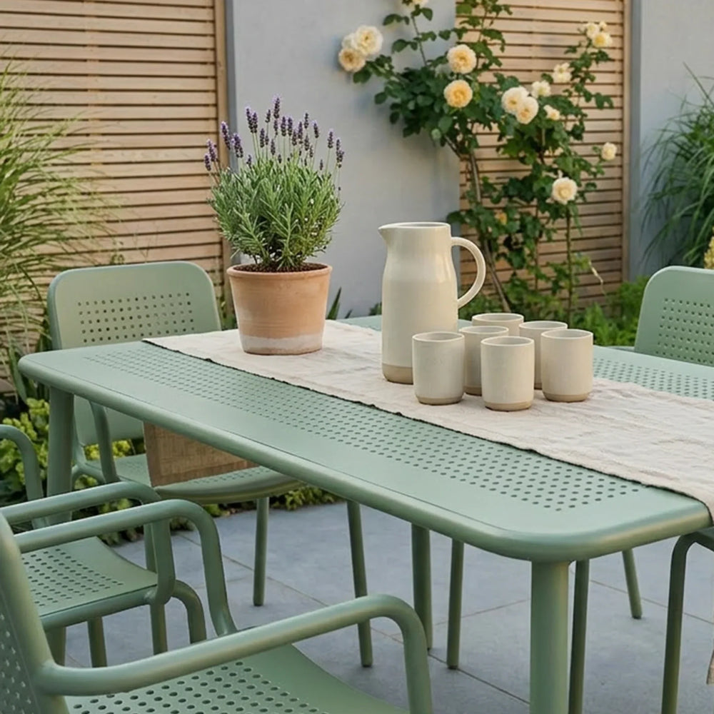 Olive green outdoor dining set with slatted chairs and table on patio, ceramic jug and cups