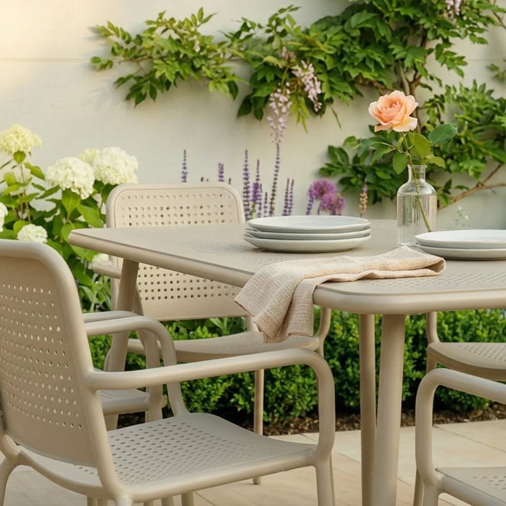 Champagne outdoor dining set with four chairs and table, garden setting, plates and vase
