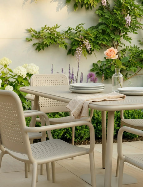 Champagne outdoor dining set with four chairs and table, garden setting, plates and vase