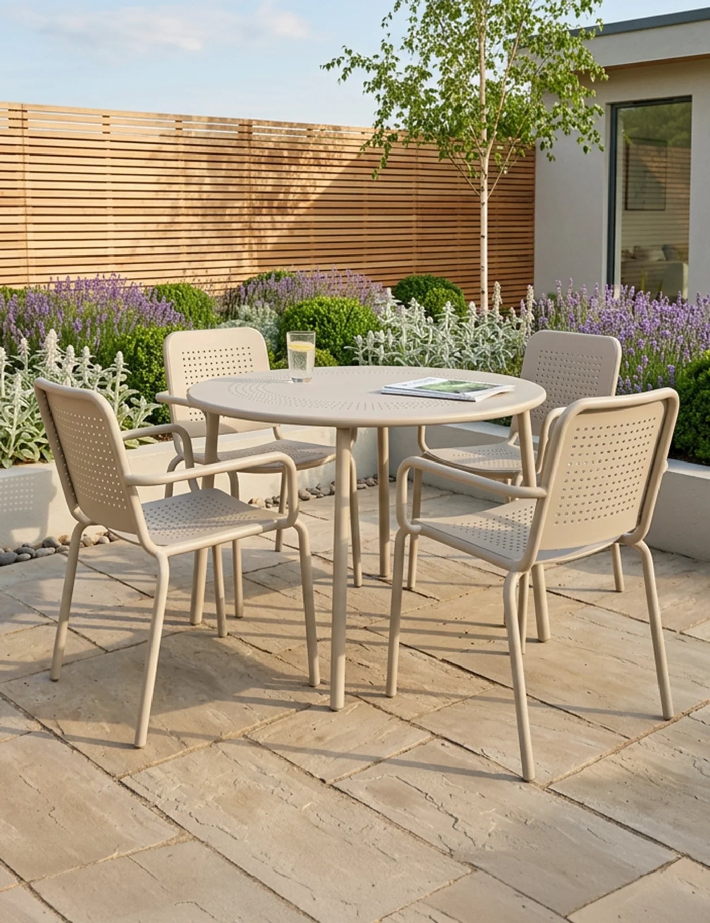Beige metal outdoor dining set with round table and four chairs on stone patio