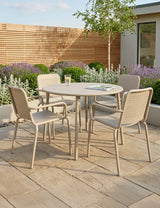 Beige metal outdoor dining set with round table and four chairs on stone patio