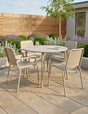 Beige metal outdoor dining set with round table and four chairs on stone patio
