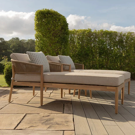 Outdoor wooden sun loungers with beige cushions and patterned pillows on a patio