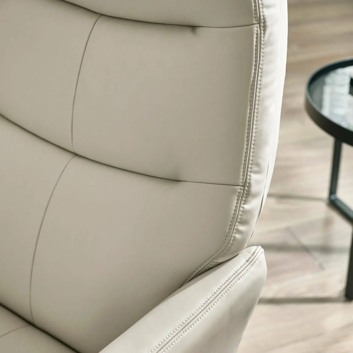 Grey accent chair close-up showing stitched leather upholstery and padded backrest