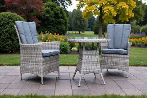 Rattan garden bistro set with two cushioned chairs and round glass top table on patio