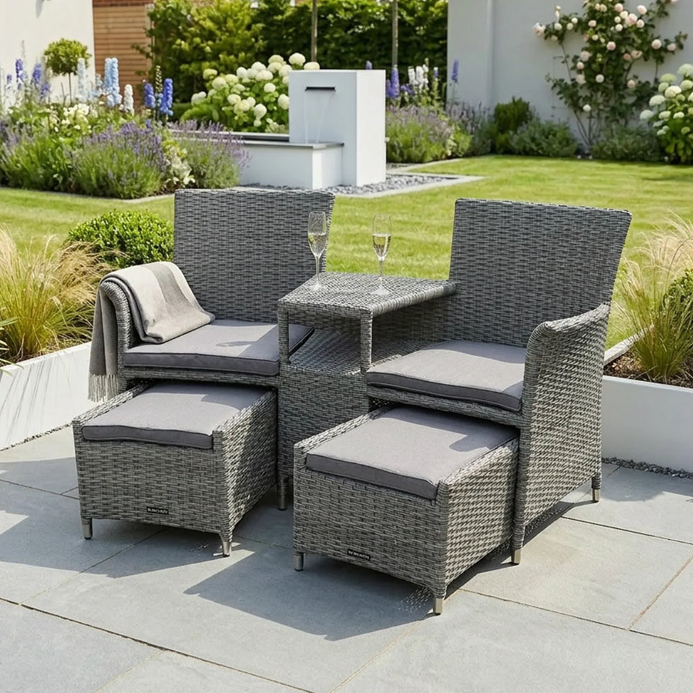 Grey rattan garden furniture set with cushions and glass tabletop on patio