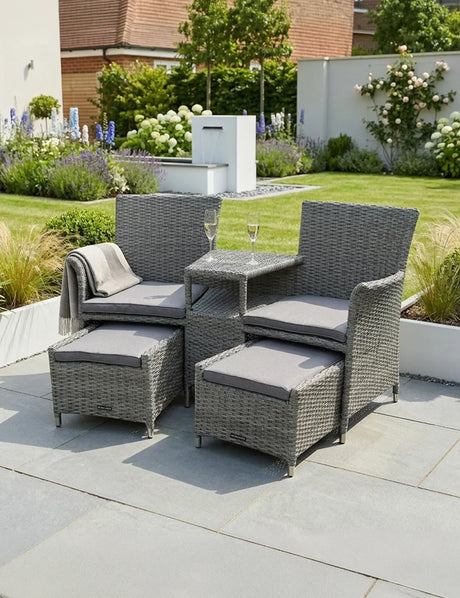 Grey rattan garden furniture set with cushions and glass tabletop on patio