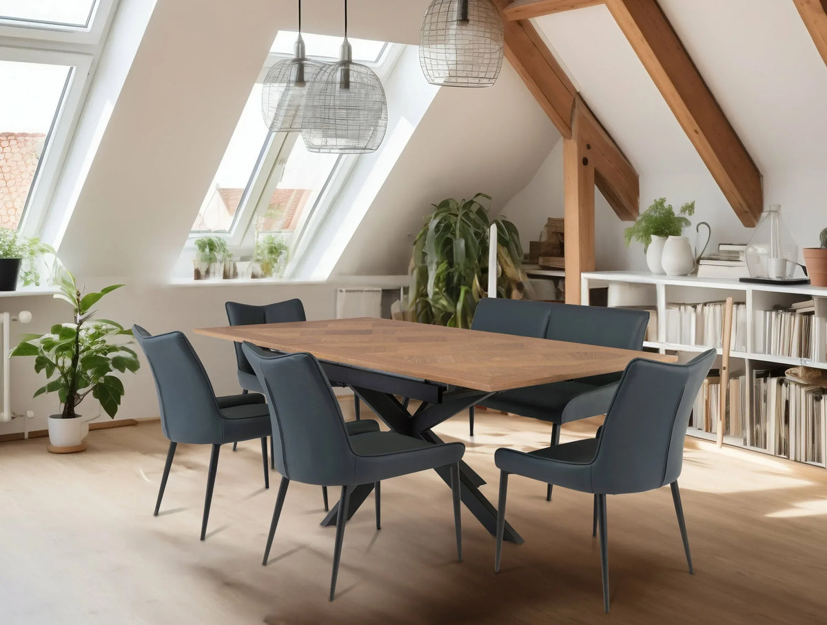 wood dining table with six dark chairs in modern loft room with skylights and plants