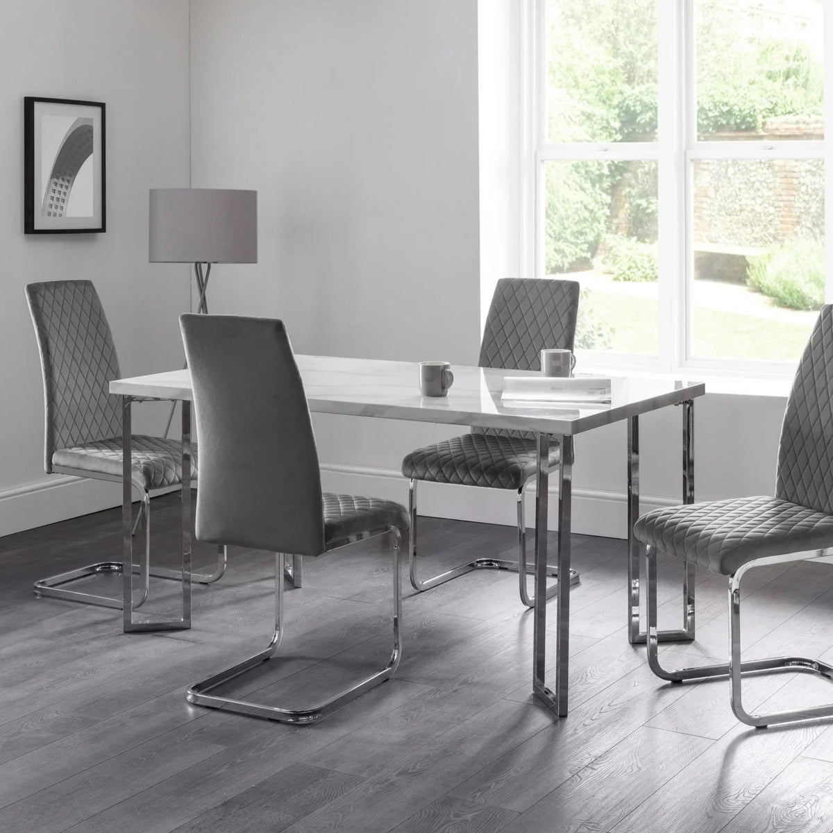 Marble dining table with chrome legs and four grey velvet cantilever chairs in modern room