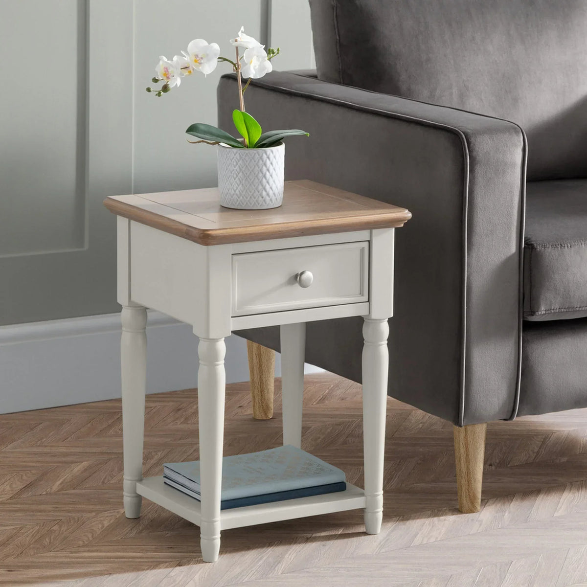 Provence lamp table with drawer and shelf beside grey sofa, potted plant on top