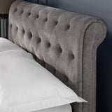 Close-up of grey fabric button-tufted wingback headboard with a white pillow edge visible