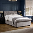 Upholstered grey fabric double bed with tufted headboard and footboard in a dark blue room.