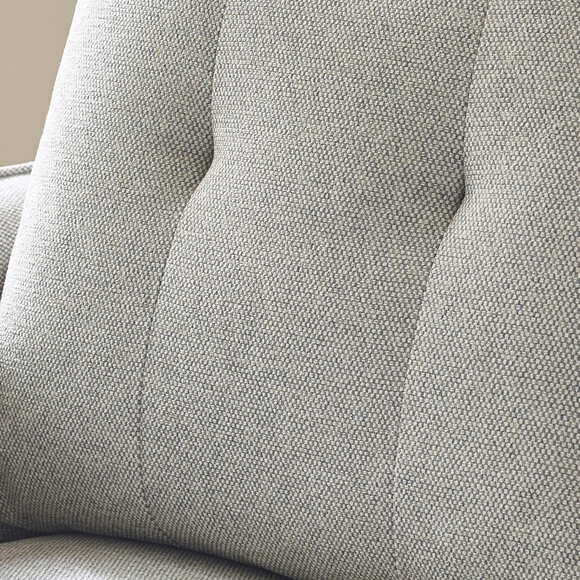 Closeup of grey fabric sofa backrest with tufted upholstery detail