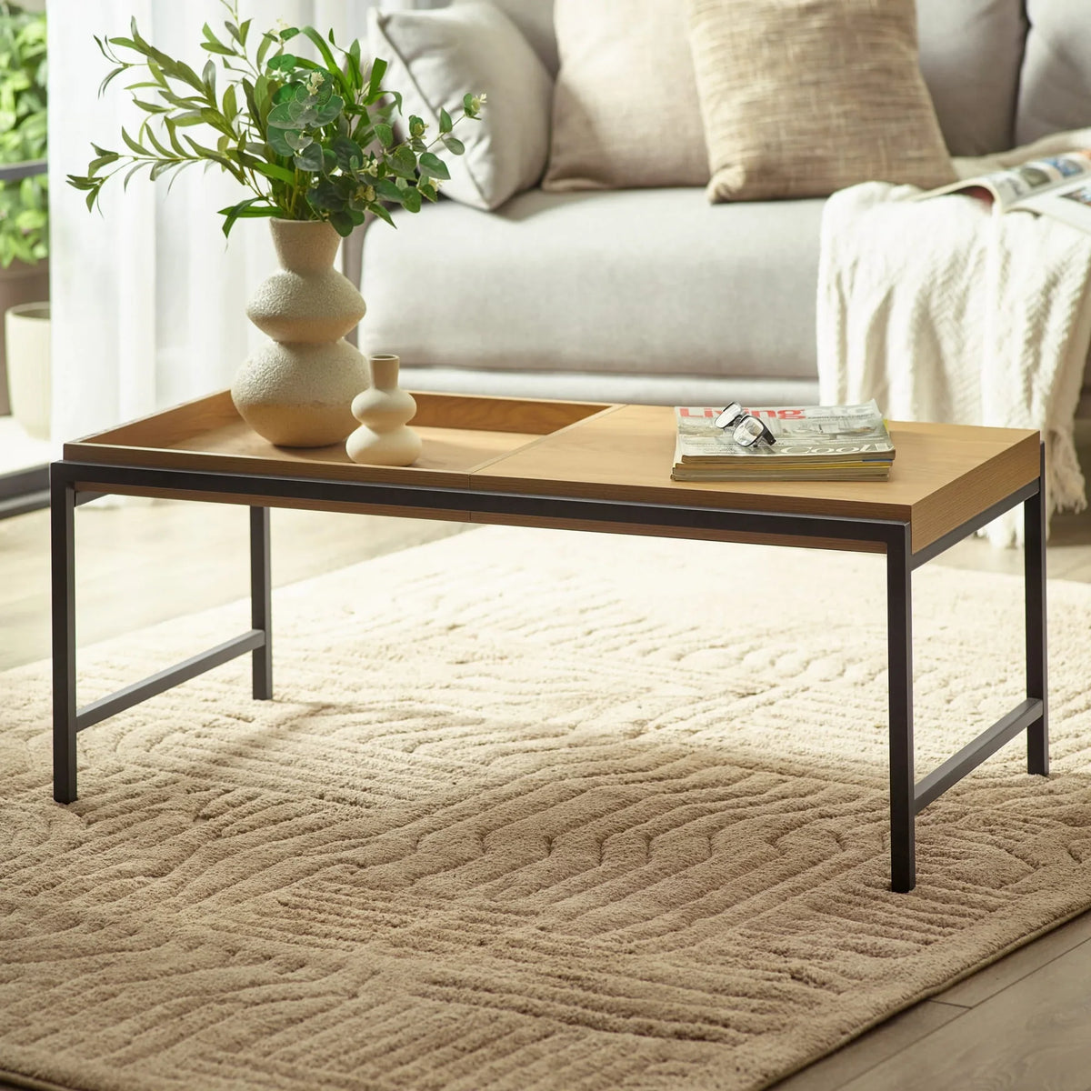 Modern wooden coffee table with black metal legs on beige textured rug in living room