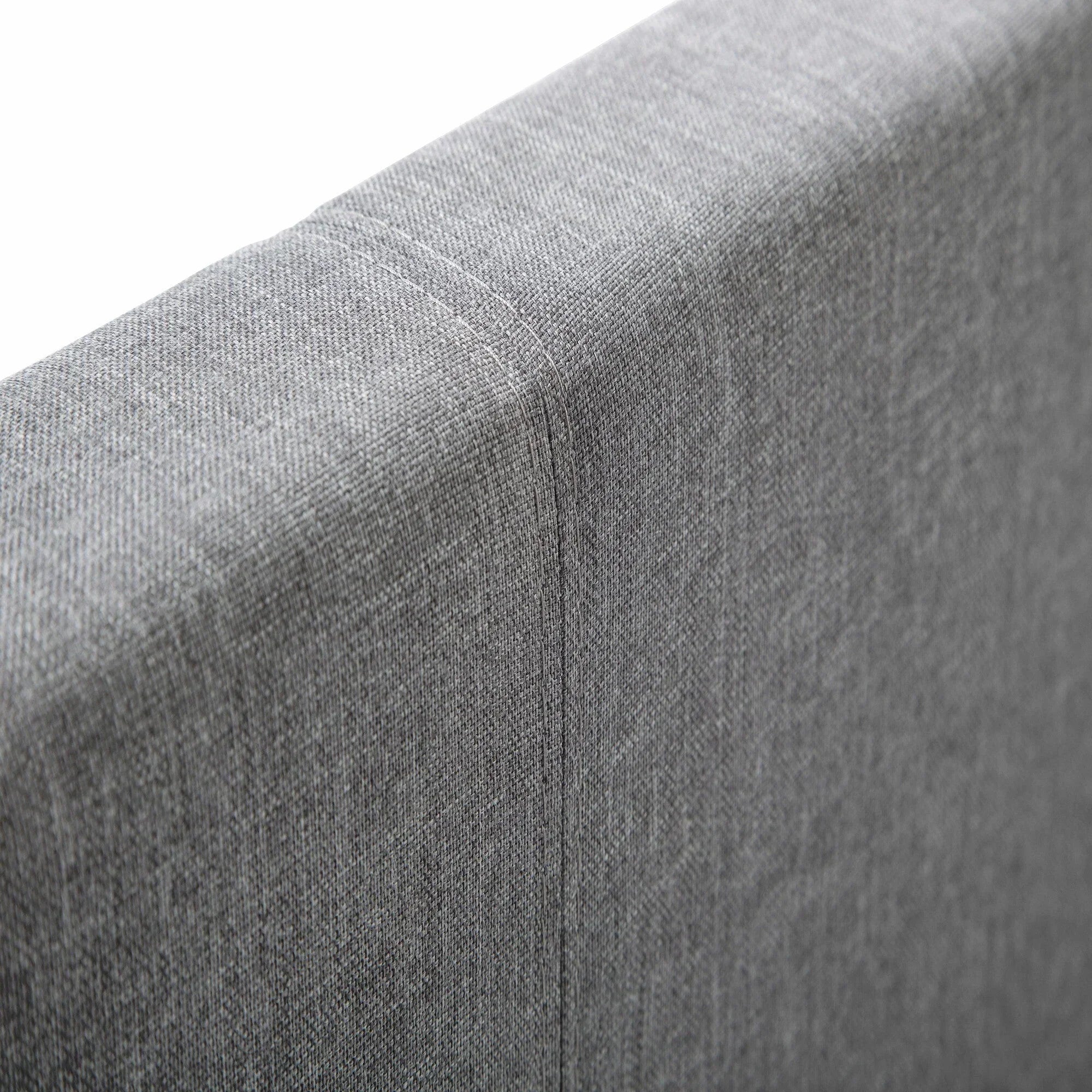 Close up of light grey linen single bed headboard showing fabric texture and stitching