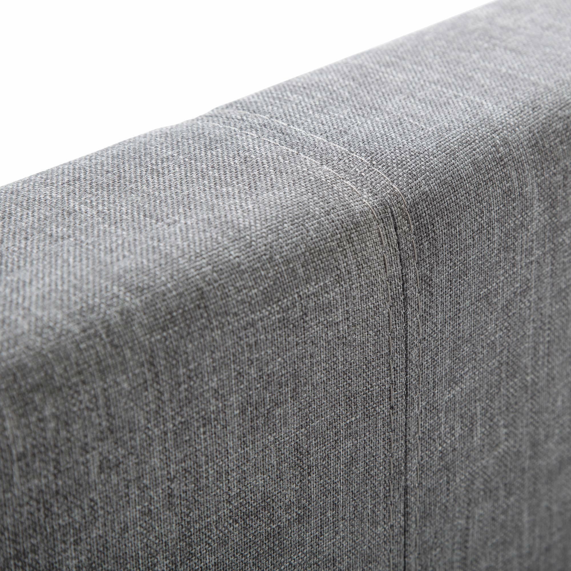 Detail of light grey linen king bed headboard upholstery with visible stitching