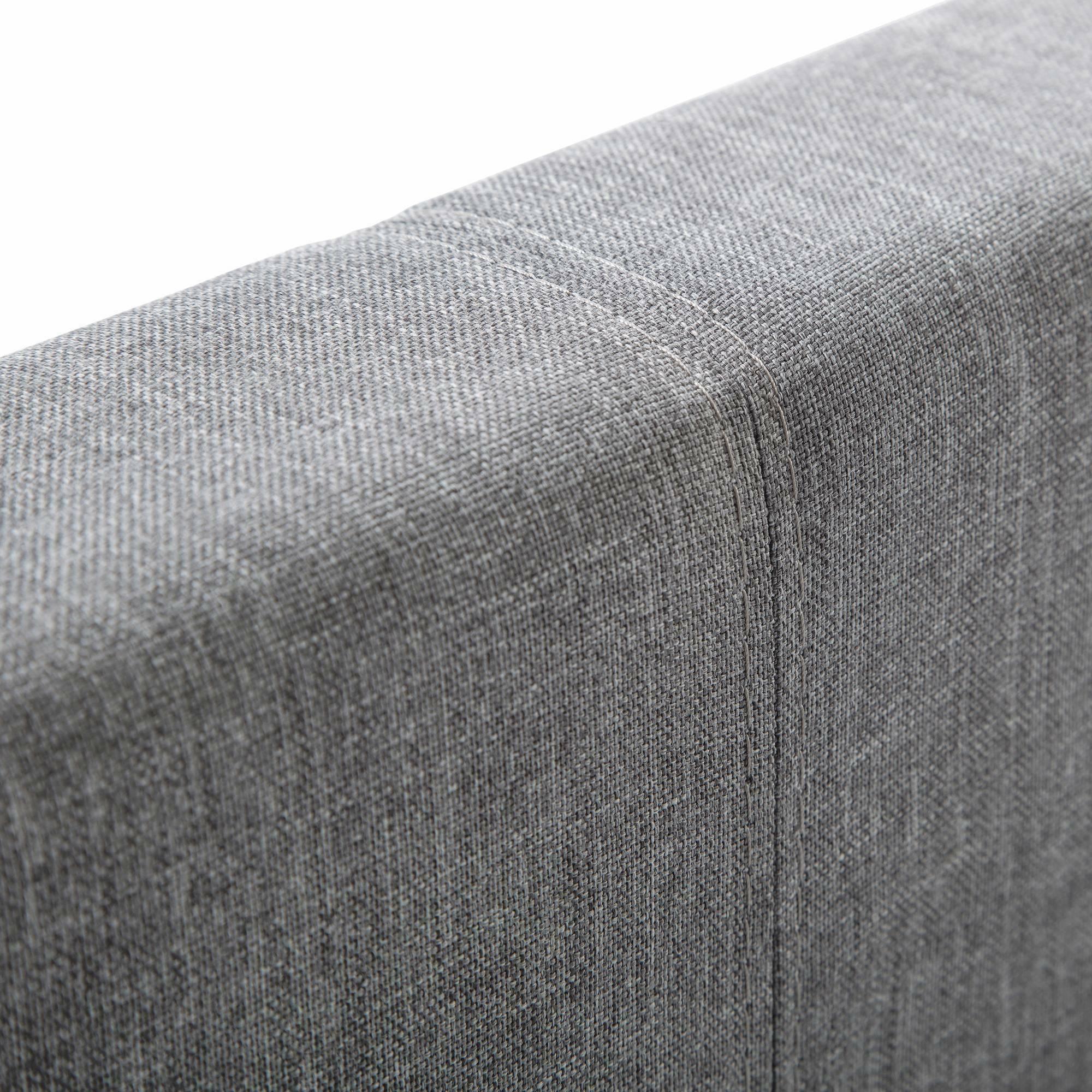 Grey fabric headboard corner with visible seam detail and textured upholstery