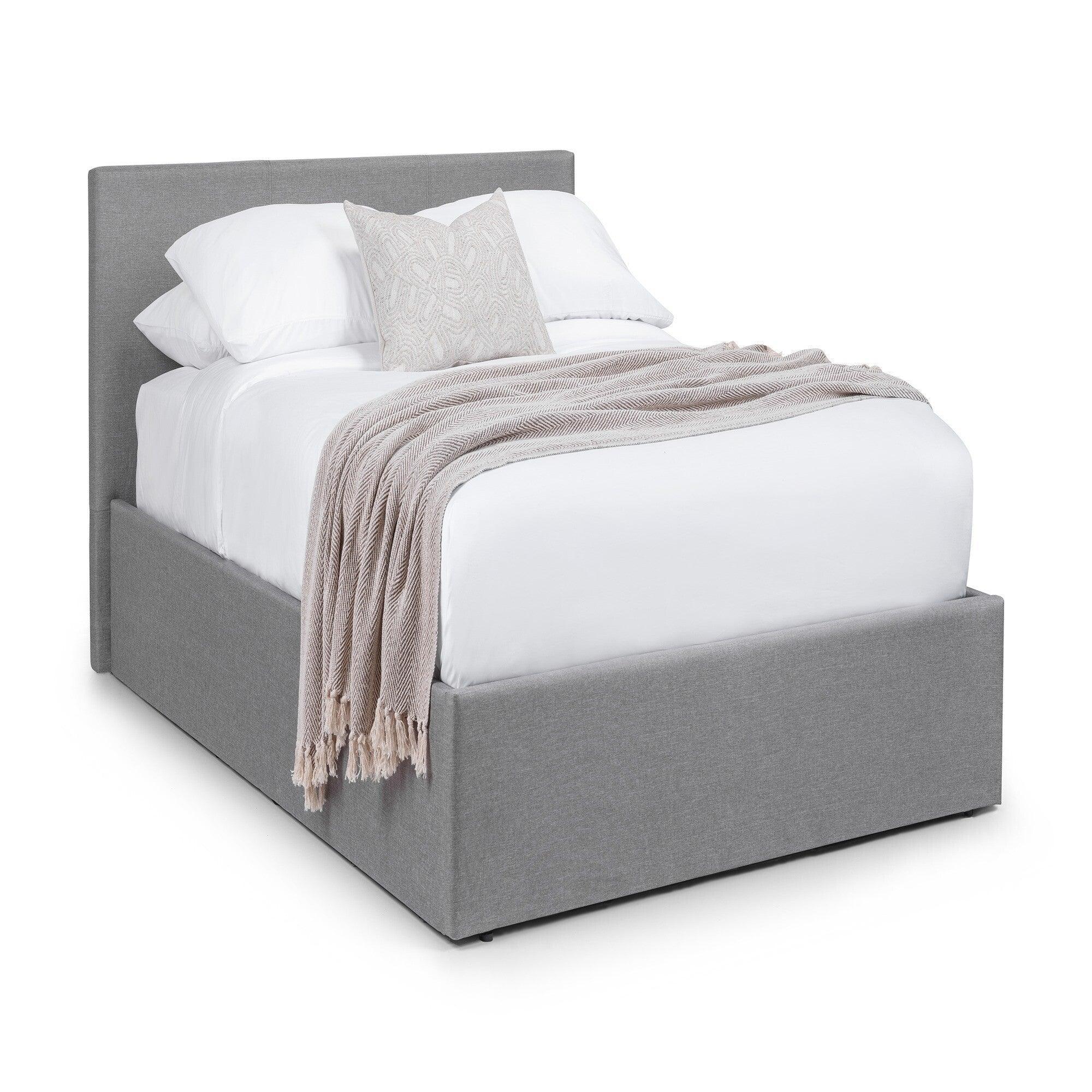 grey upholstered storage bed with headboard, white bedding and beige throw blanket