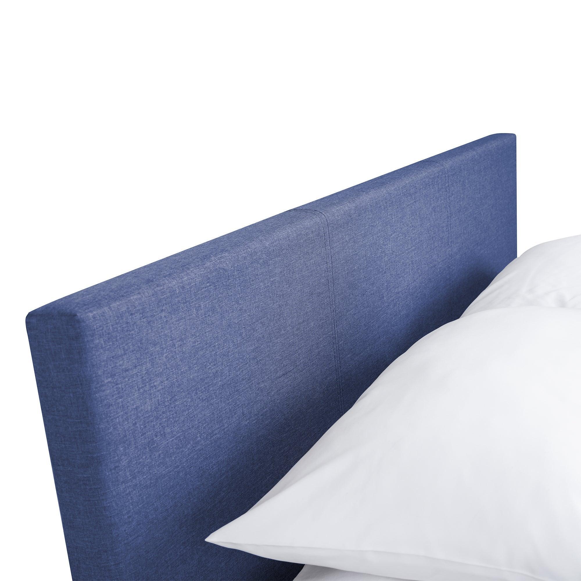 Blue upholstered storage bed headboard close-up with white pillow
