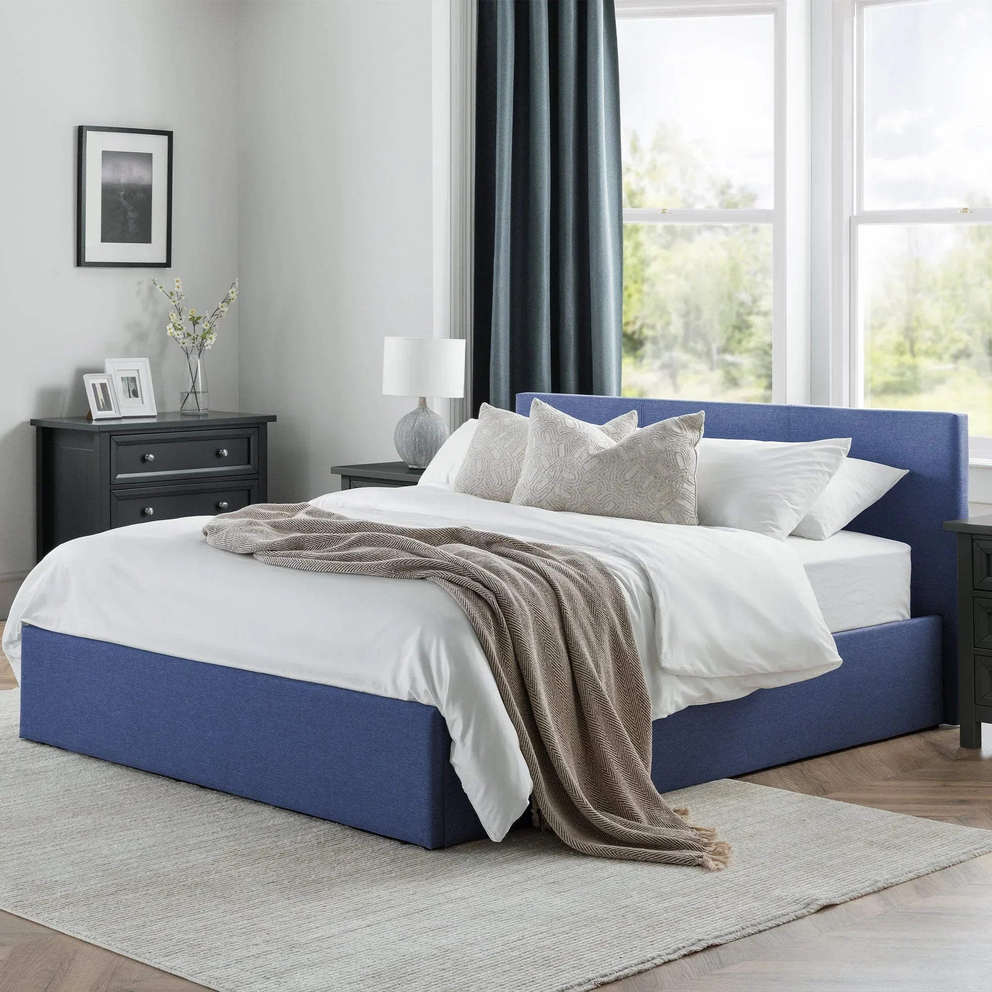 Blue lift-up storage bed with headboard in modern bedroom setting on grey rug