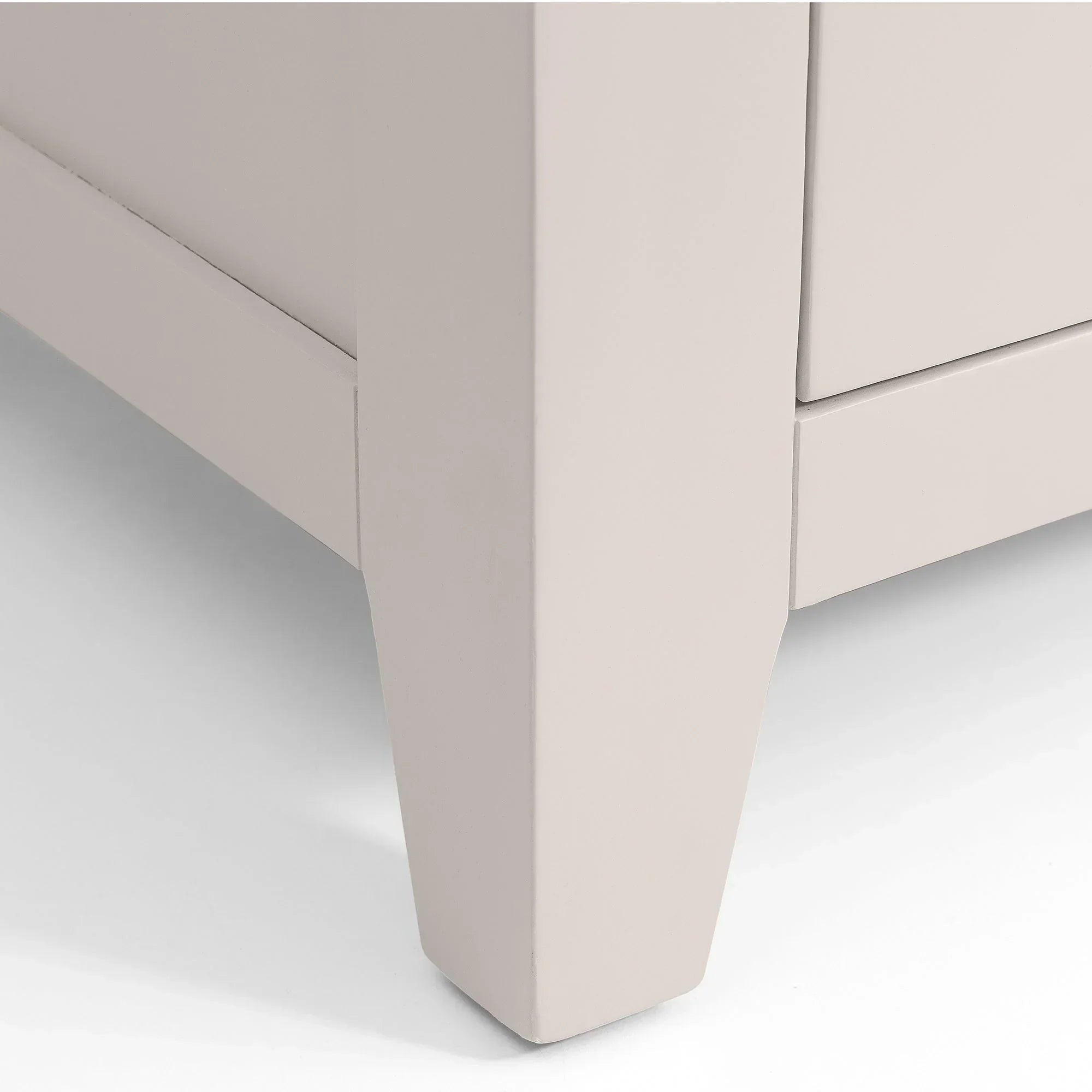 Closeup of beige bedside table leg and lower drawer corner
