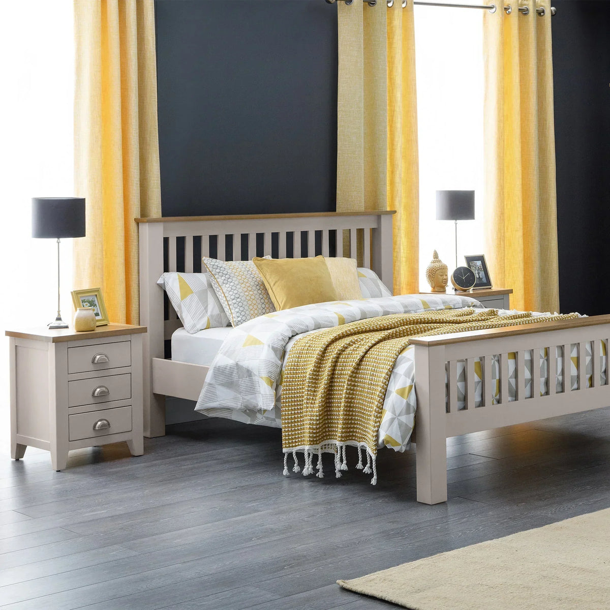 Three drawer bedside table in light wood beside bed with grey and yellow bedding