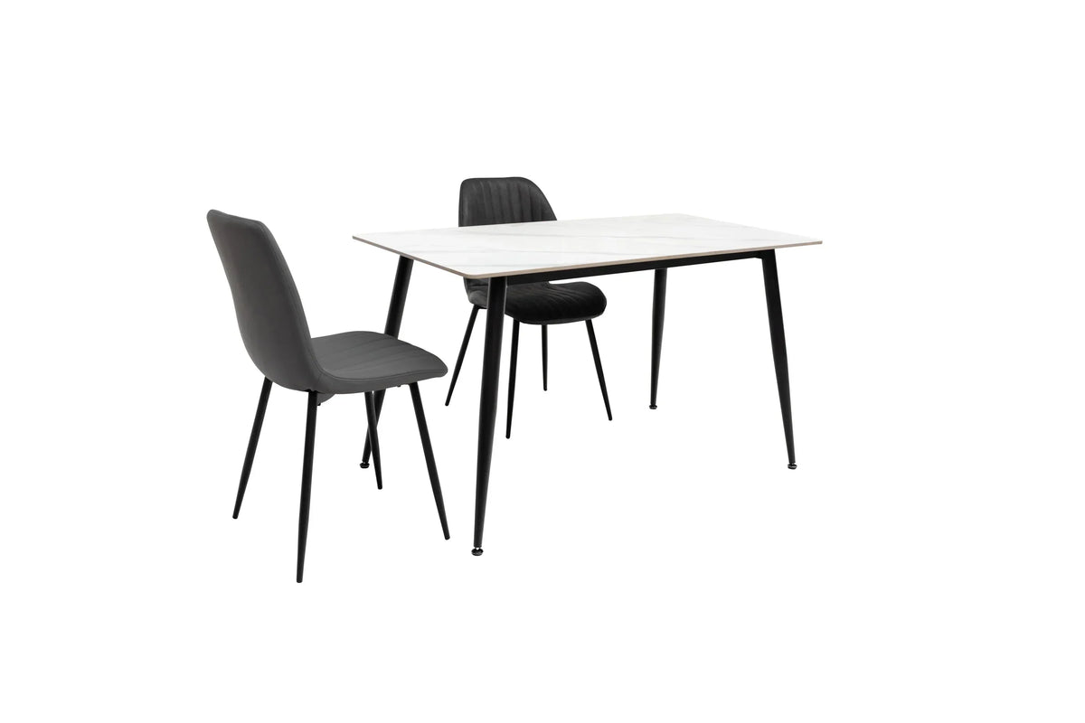 Black dining chairs with slim metal legs and marble effect dining table, angled view