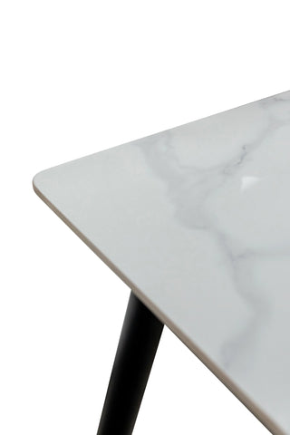 Close-up of white marble dining table top with black angled metal leg