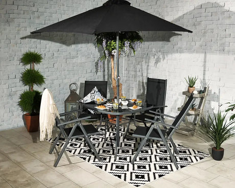Black garden furniture set with round glass table, chairs, umbrella and geometric rug