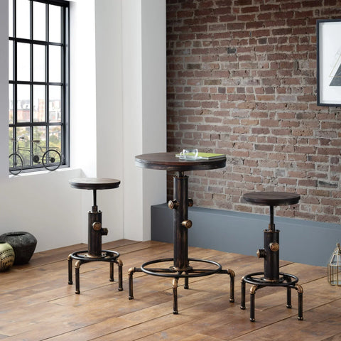Industrial bar table and two round stools with metal base and dark wood seats in loft setting
