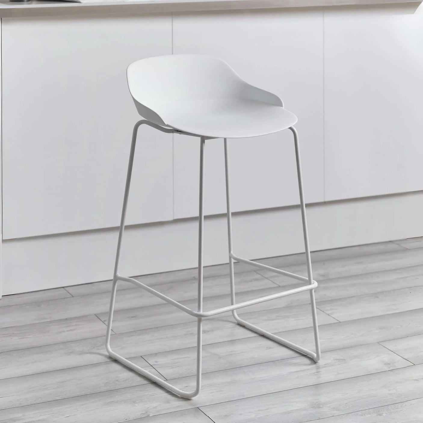 White bar stool with curved seat and metal legs in modern kitchen setting
