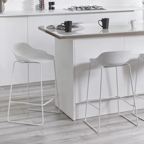 White bar stools with low backs and metal legs at a modern kitchen island
