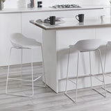 White bar stools with low backs and metal legs at a modern kitchen island