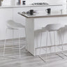 White bar stools with low backs and metal legs at a modern kitchen island
