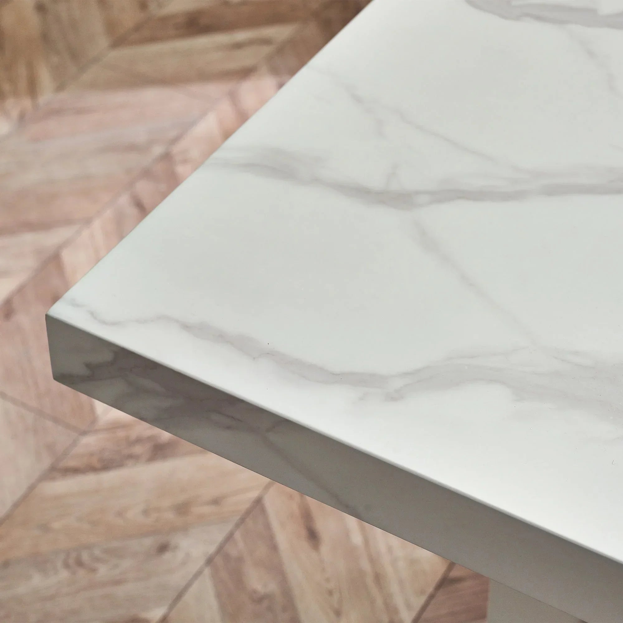 White marble effect dining table corner with grey veining and wood floor background