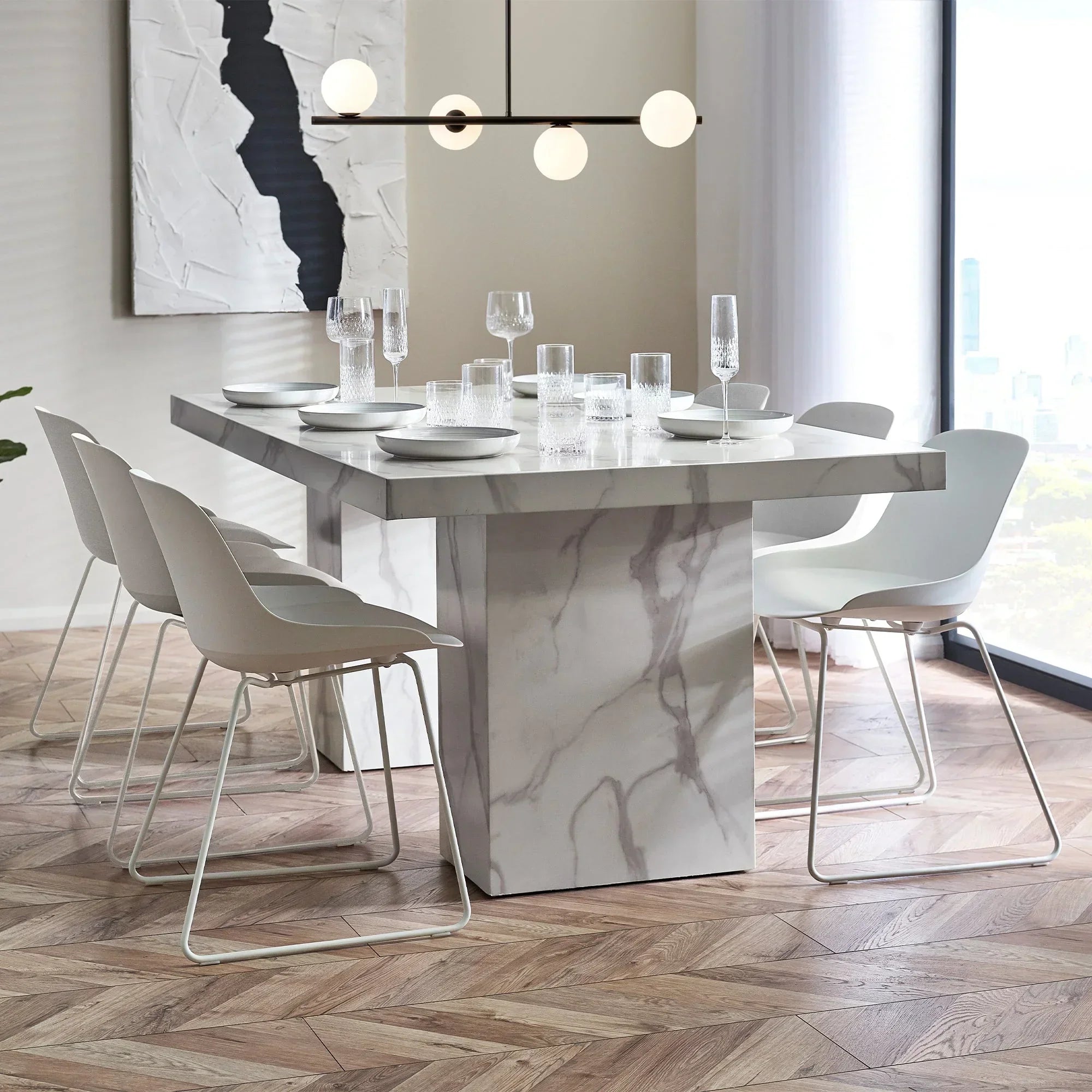 White marble effect dining table with six modern white chairs in a bright dining room