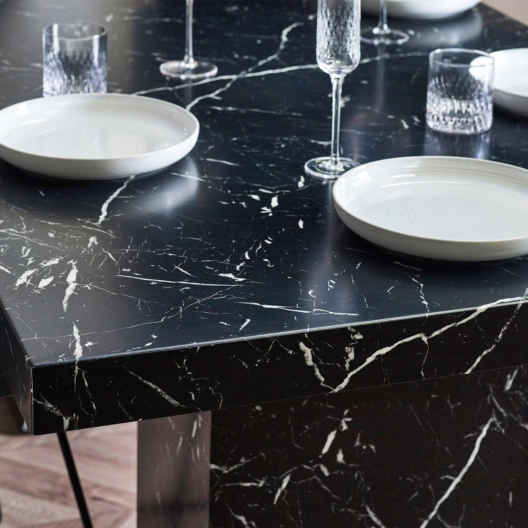 black marble effect dining table with white plates and glassware close up